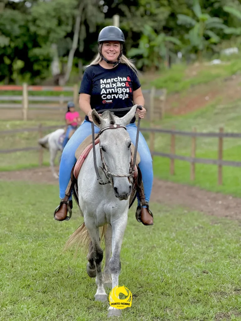Aluna montando um cavalo no haras